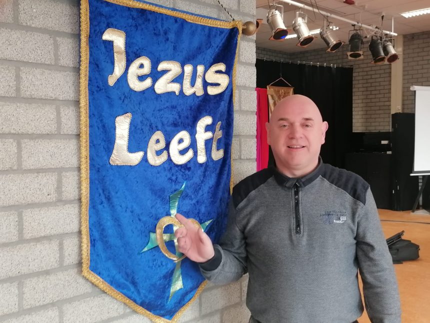 Richard met op de achtergrond een banner met de tekst 'Jezus Leeft'