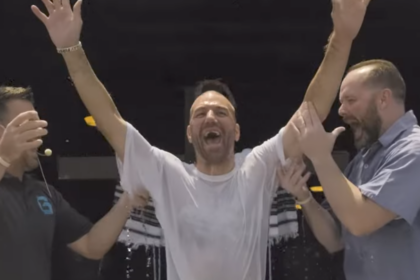 Screenshot van gevangene die gedoopt wordt in gevangenis, staat met blijdschap op uit doopbad