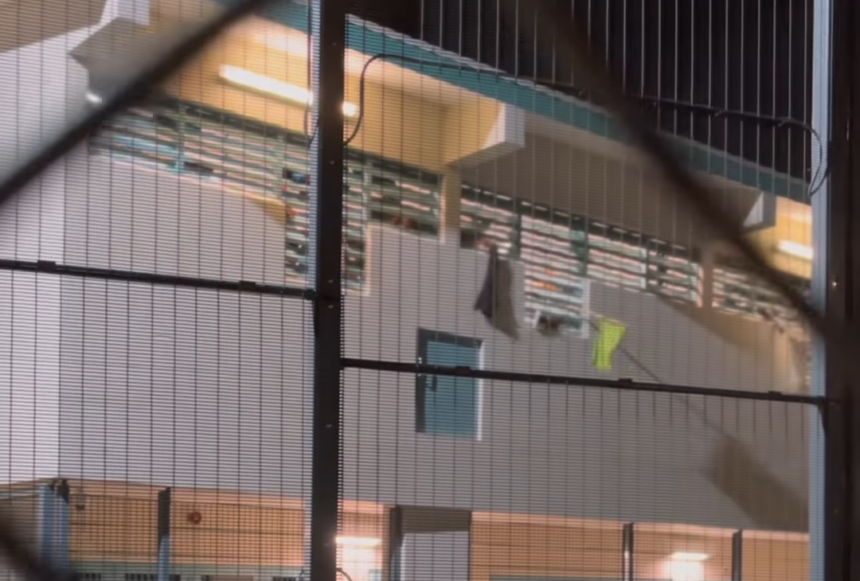 Screenshot van gevangenen die vanuit hun cel met doeken zwaaien en reageren op evangelisatie