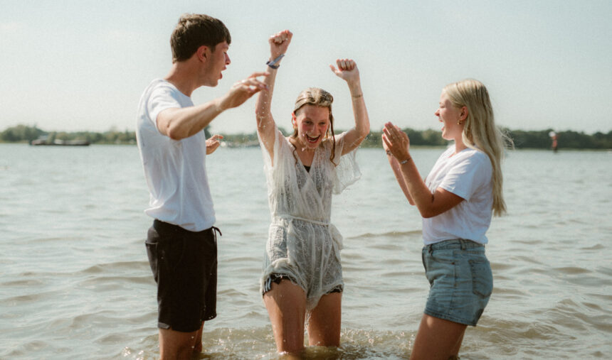 Jonge vrouw wordt gedoopt op strand Horst